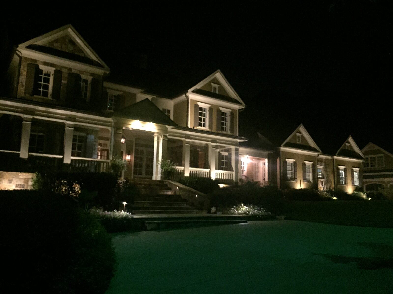 Craftsman home with wraparound porch lit evenly across the full facade.